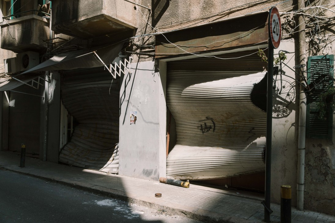 Severely damaged and crumpled steel security shutters of storefronts twisted and warped by the explosion's powerful pressure wave