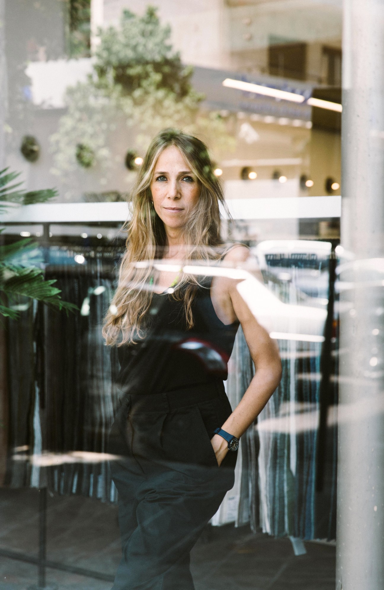 Fashion entrepreneur Tala Hajjar standing in workspace with fabrics and materials used to cover damaged windows