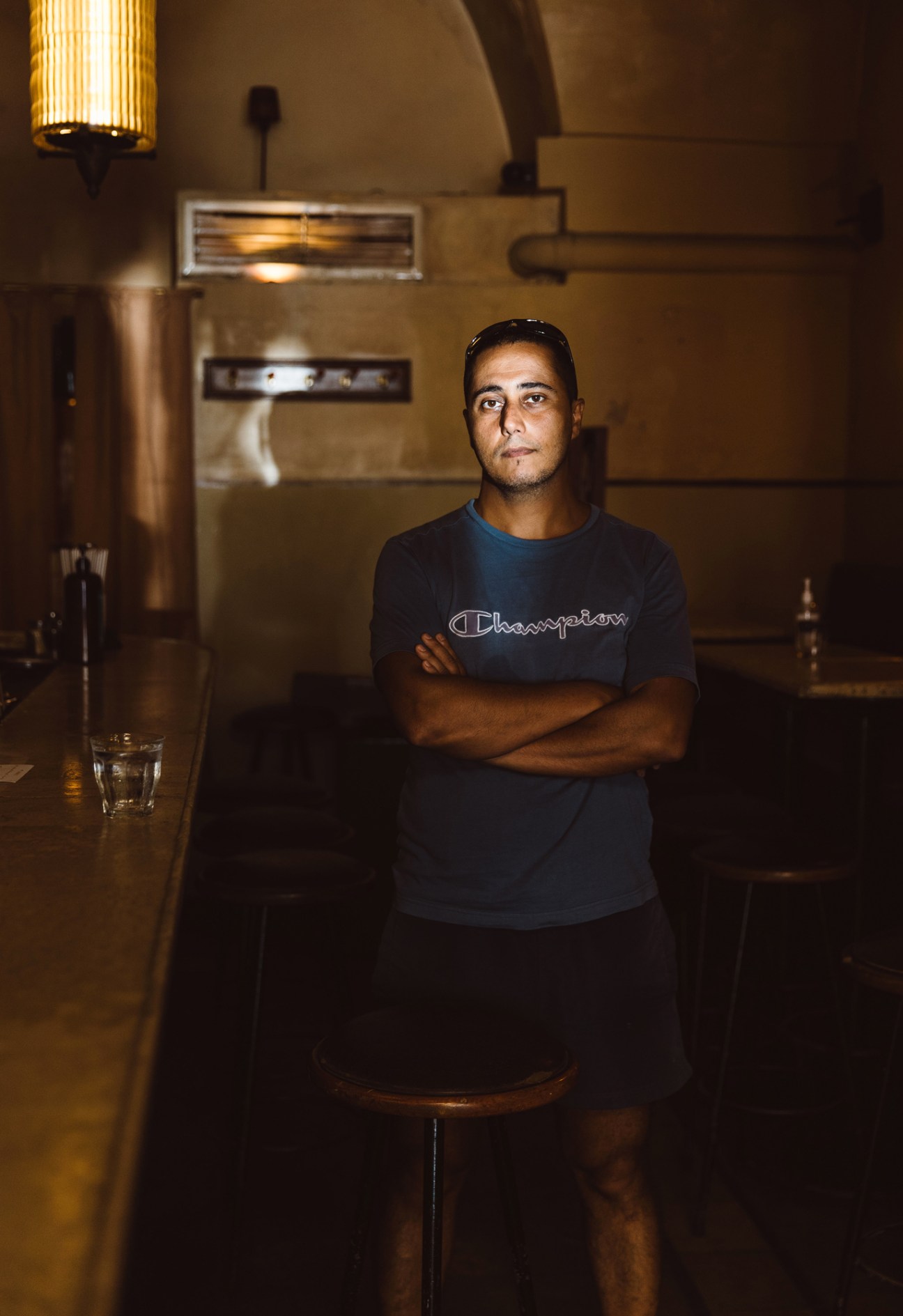 Nino Aramouni, owner of the Dragonfly bar, standing with arms crossed in his stone-arched establishment