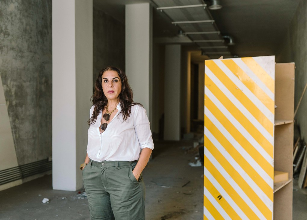 Designer Rana Salam standing in her damaged boutique surrounded by broken glass and destroyed merchandise