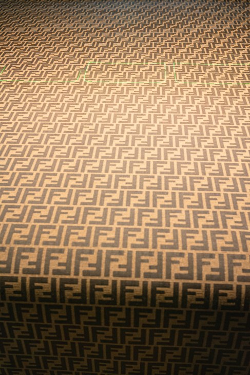 Close-up view of golden-brown fabric with repeating FF logo pattern in geometric grid formation