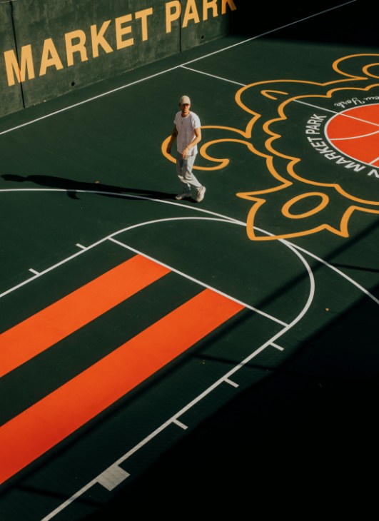 Basketball court at Washington Market Park with pine-green base and orange and yellow striped design