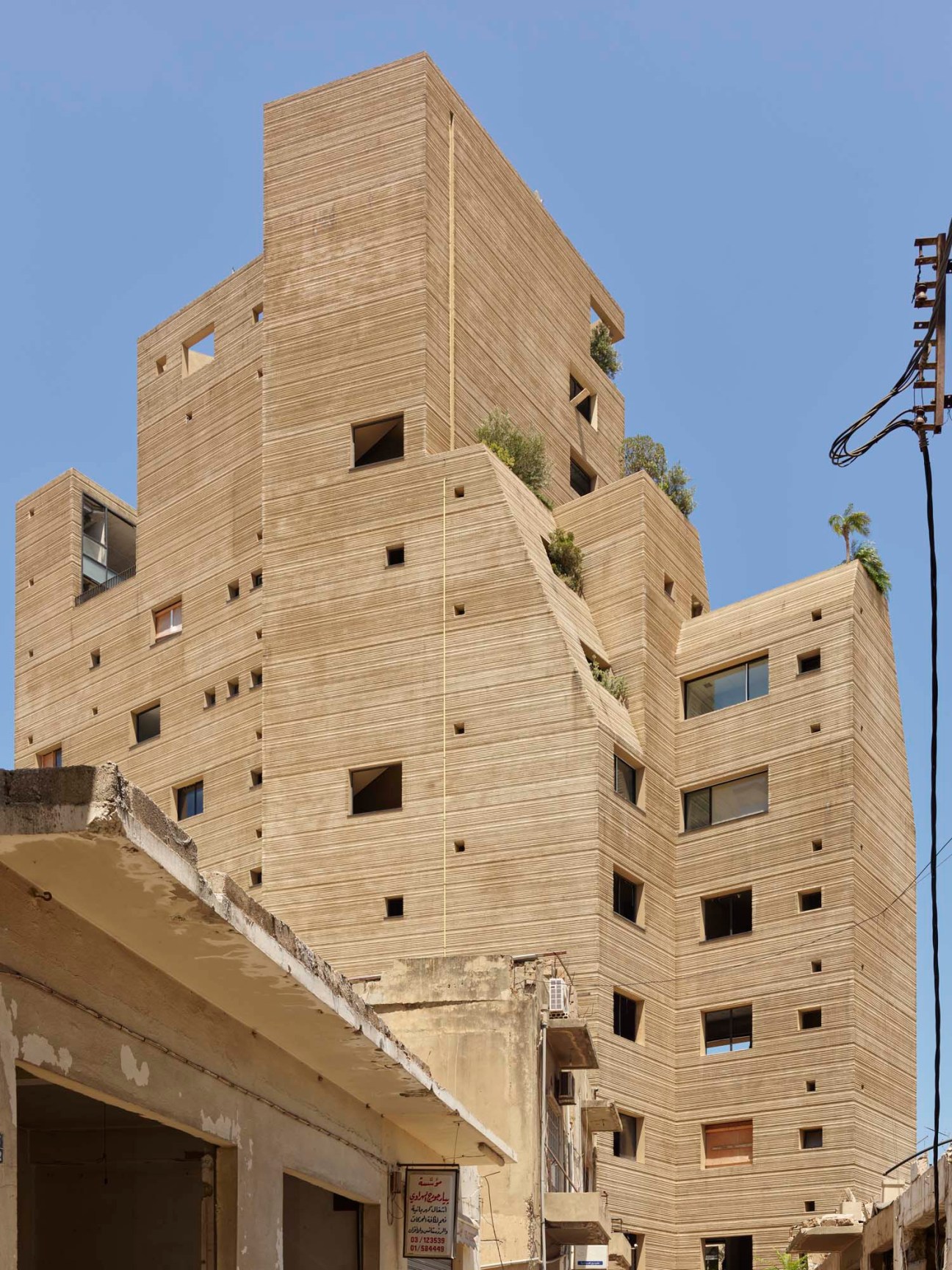 Stone Garden apartment building in Beirut with distinctive hand-combed textured facade and irregular window voids designed by Lina Ghotmeh.