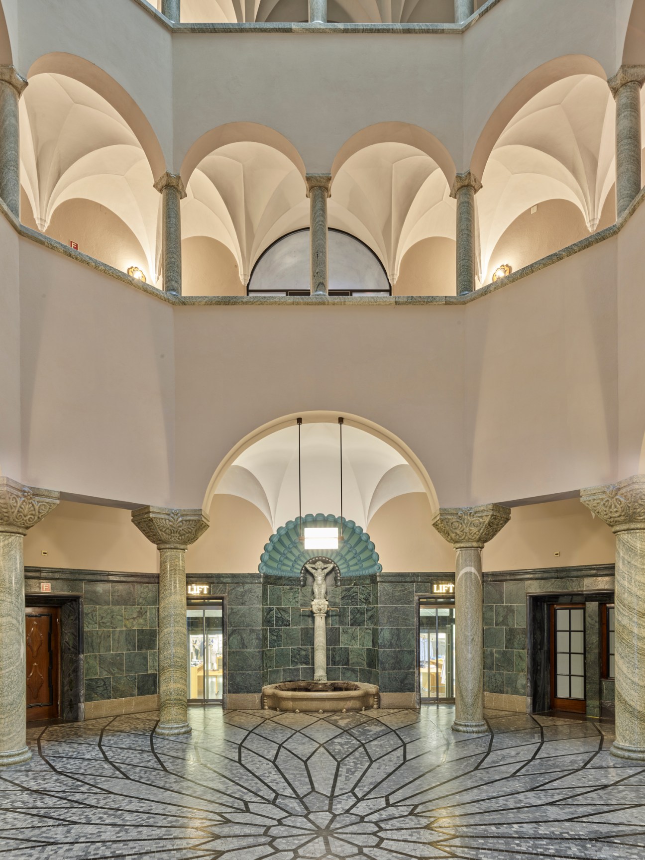 Grand banking hall with marble columns, vaulted ceilings, decorative fountain and geometric floor pattern