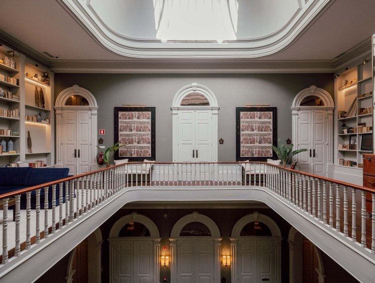 Elegant library interior at Torel 1884 with high ceilings, arched doorways, wooden railings and built-in bookshelves.