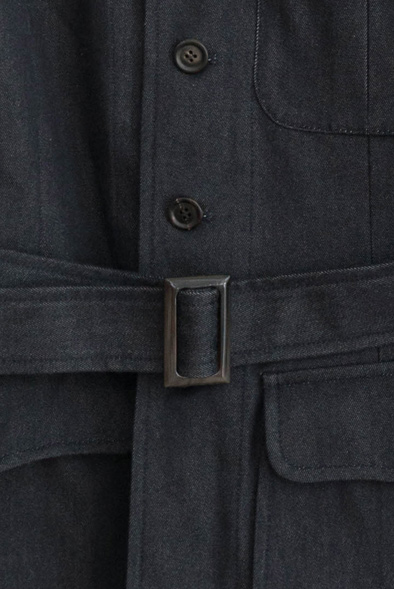 Close-up of dark navy jacket with belt buckle and buttons showing tailored construction details