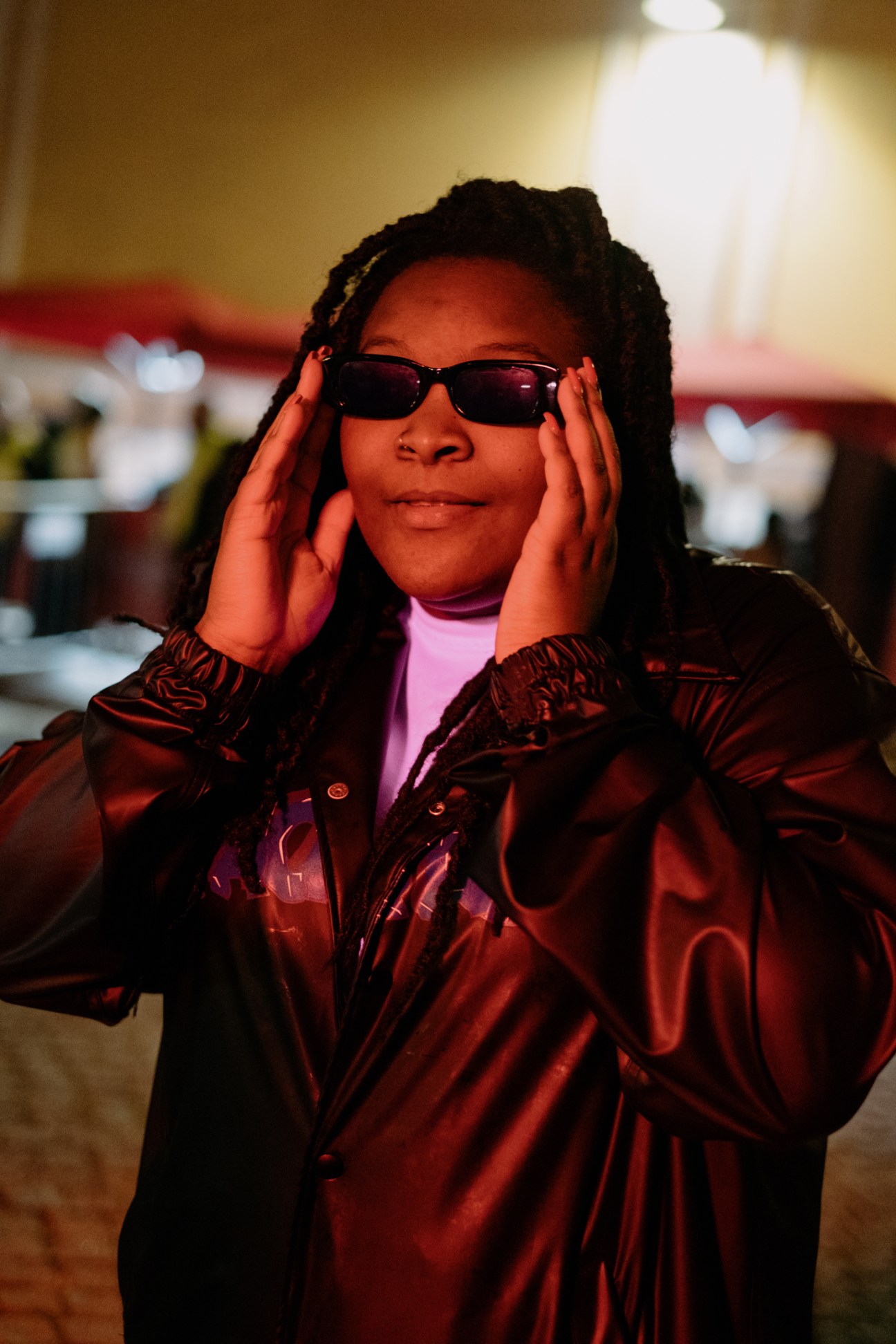 Nídia wearing sunglasses and a reflective jacket with hands framing her face at Sónar festival