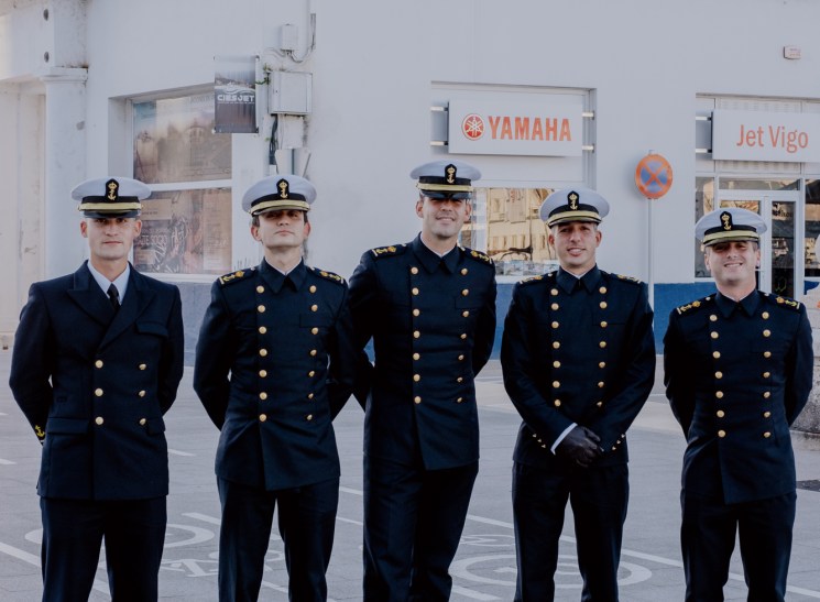 Five naval officers in dress uniform posing outdoors.