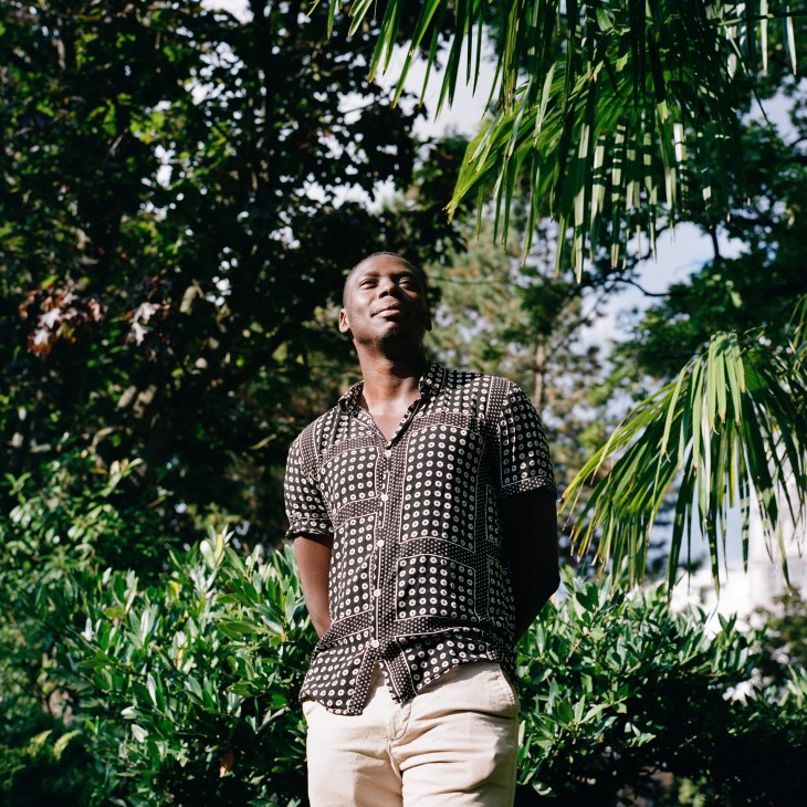 Elgas, a local writer, standing outdoors among tropical vegetation in Dakar