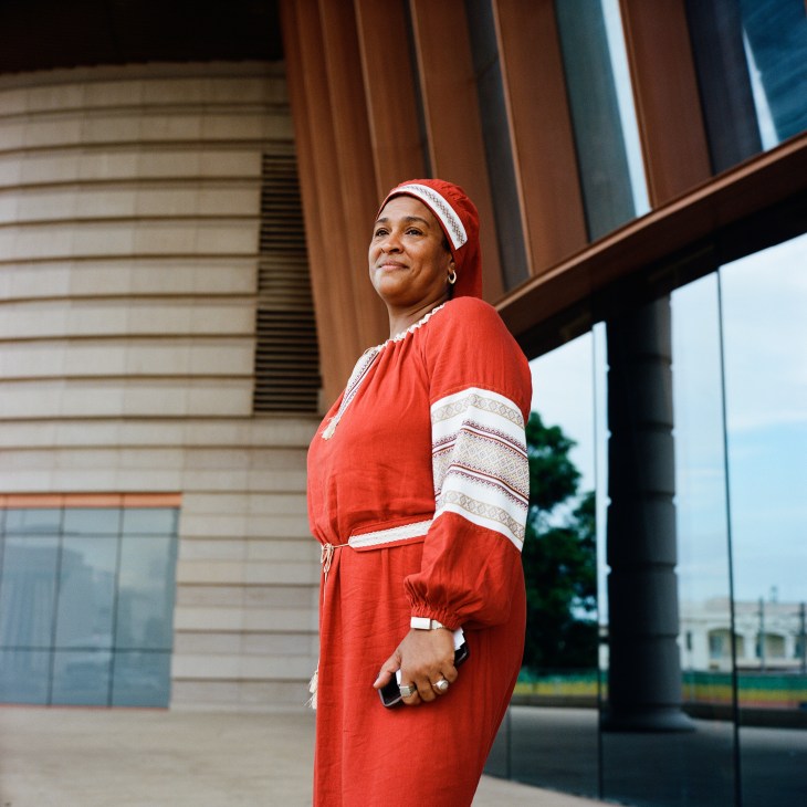 Russian-Senegalese consultant Oumy Sène wearing traditional red dress standing outside modern building