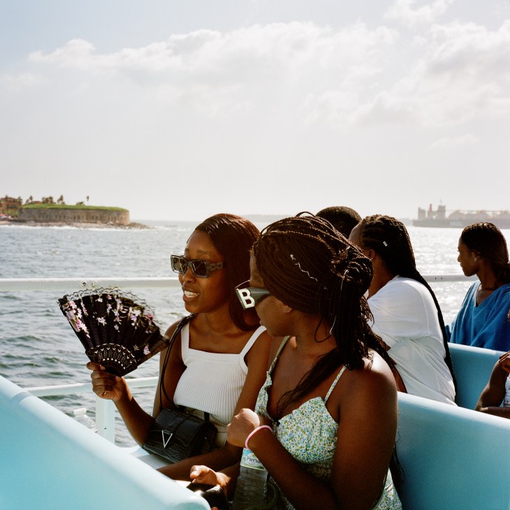 Young women on a boat enjoying a sunny day on the water with coastal cityscape in background