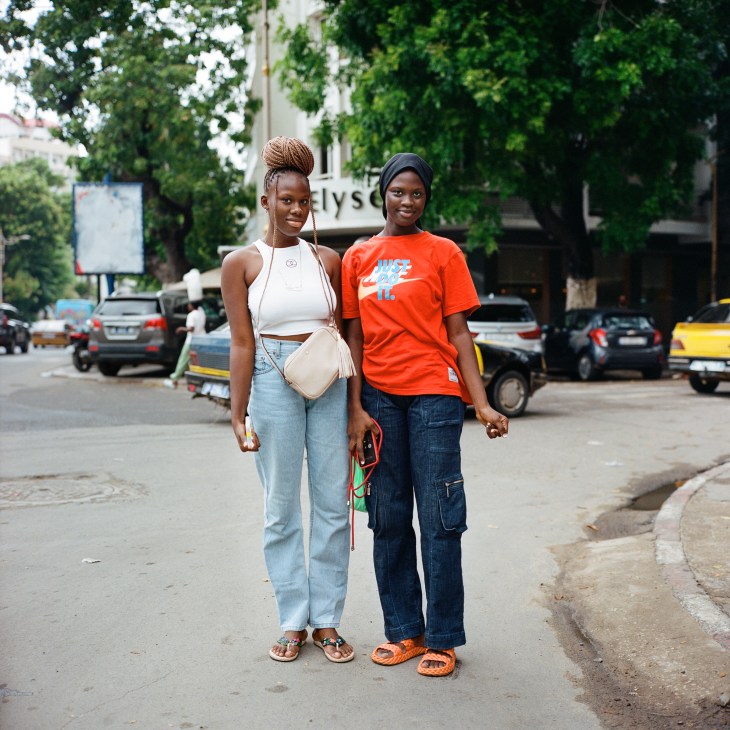 Two young women standing together on a street in Dakar