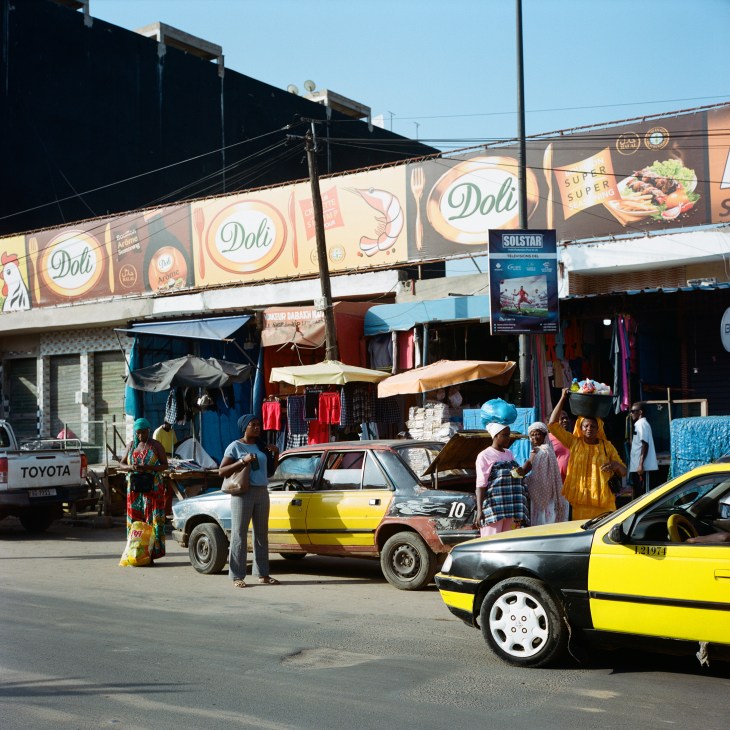 Street scene with yellow taxi cars and people on a busy road in Dakar