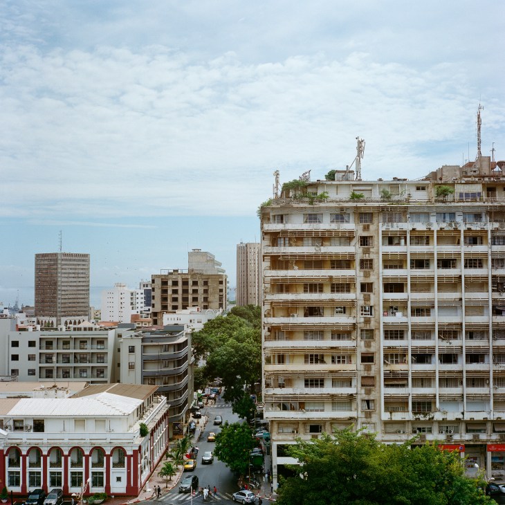 Urban street scene with multi-story residential and commercial buildings in Dakar