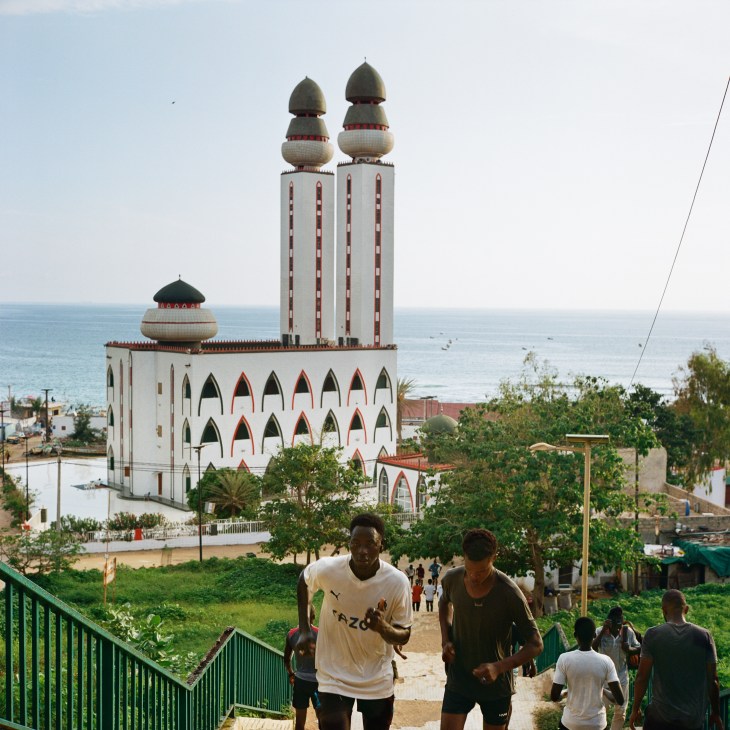 Large white mosque with twin minarets topped by green and white domes overlooking the Atlantic Ocean
