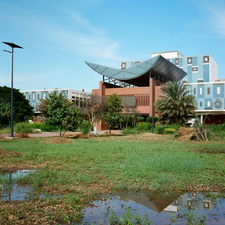 Modern university buildings with distinctive curved metal roof structure and geometric facade design