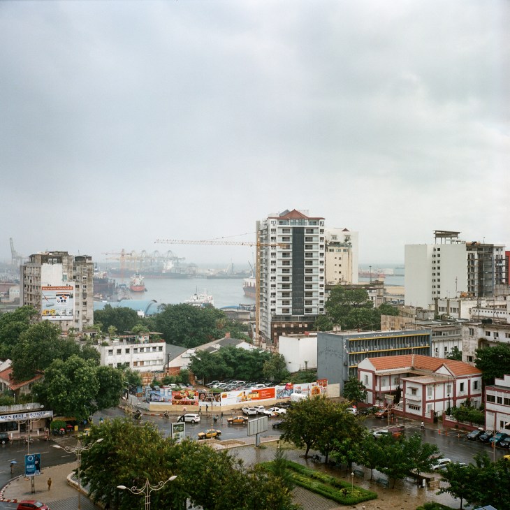 Aerial view of Dakar cityscape with modern buildings, harbor with cranes and ships visible in background