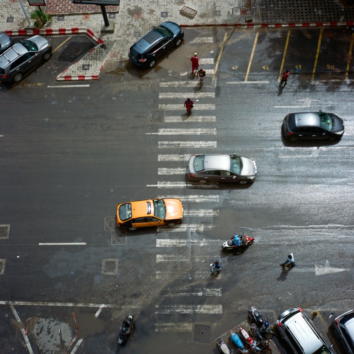 Aerial view of flooded street intersection with cars navigating through standing water and crosswalk