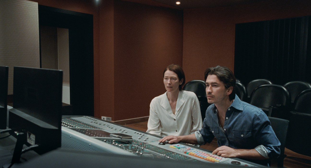 Two people working at a sound mixing console in a professional recording studio