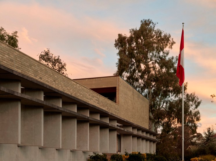 Low modernist building with a red flag at sunset.