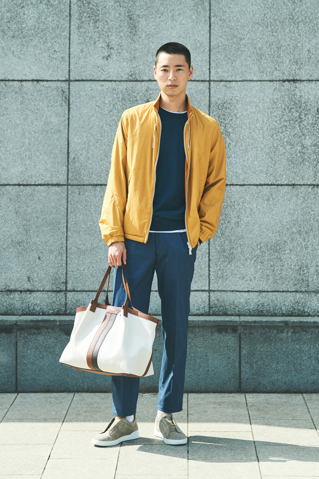 Model wearing Ermenegildo Zegna jacket, jumper, t-shirt and trousers with Serapian bag
