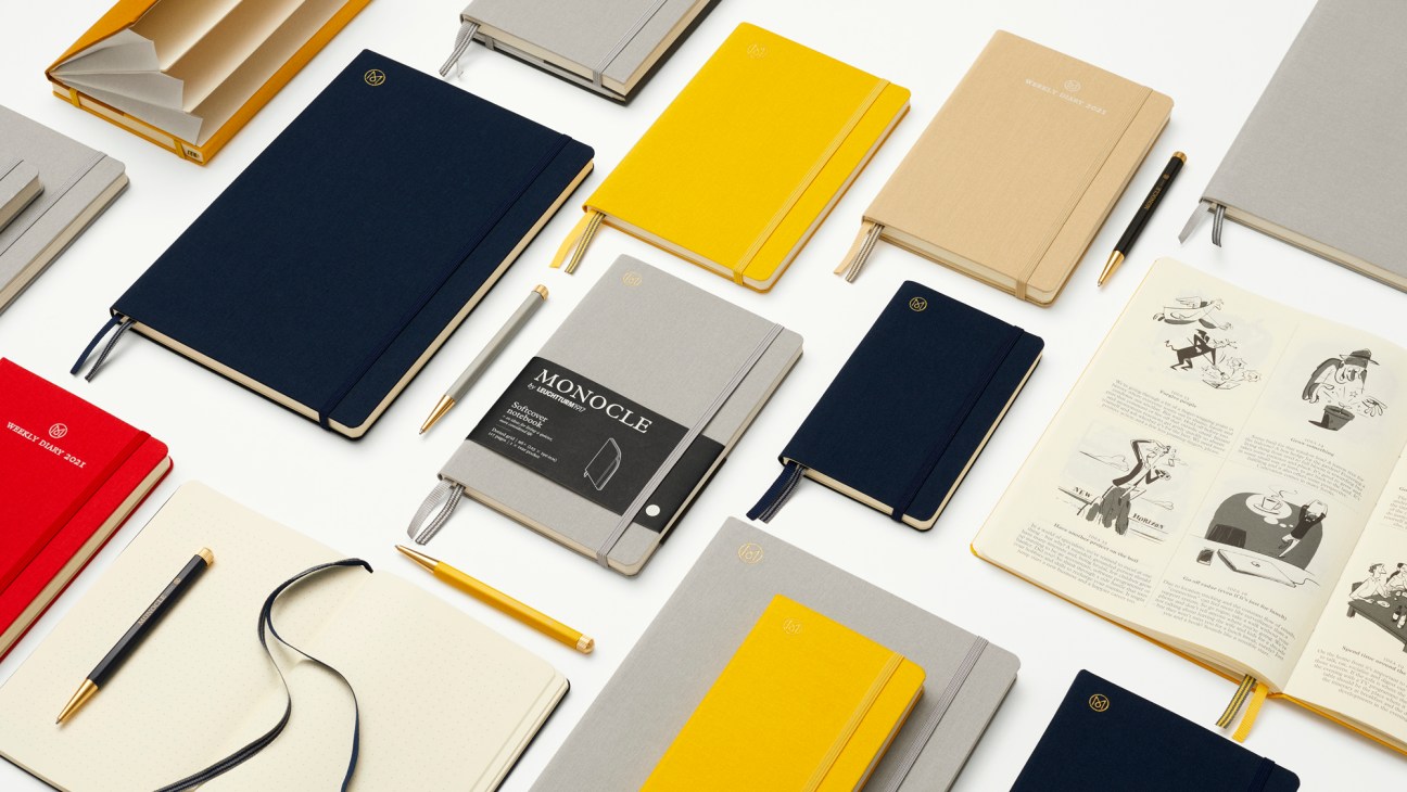Collection of Monocle x Leuchtturm1917 linen notebooks in various colors and sizes arranged on white surface