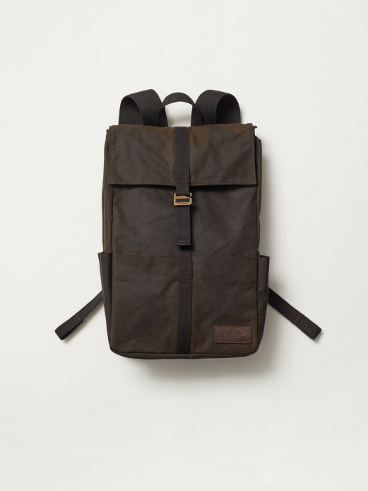 Brown Barbour backpack with waxed cotton fabric and black straps against neutral background