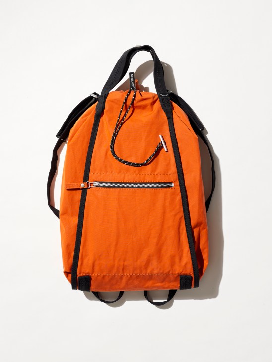 Qwstion backpack made from sustainable banana fiber material in natural brown tone, an orange backpack with black straps and zipper pocket photographed against white background