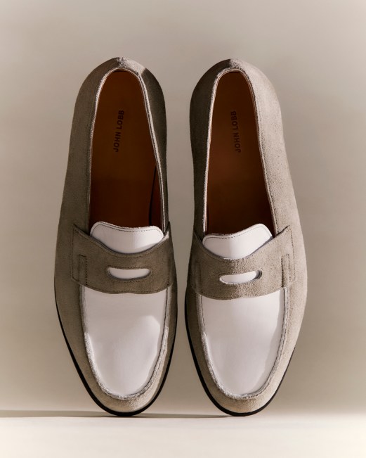 Pair of two-tone suede loafers in beige and white with penny strap detail on neutral background