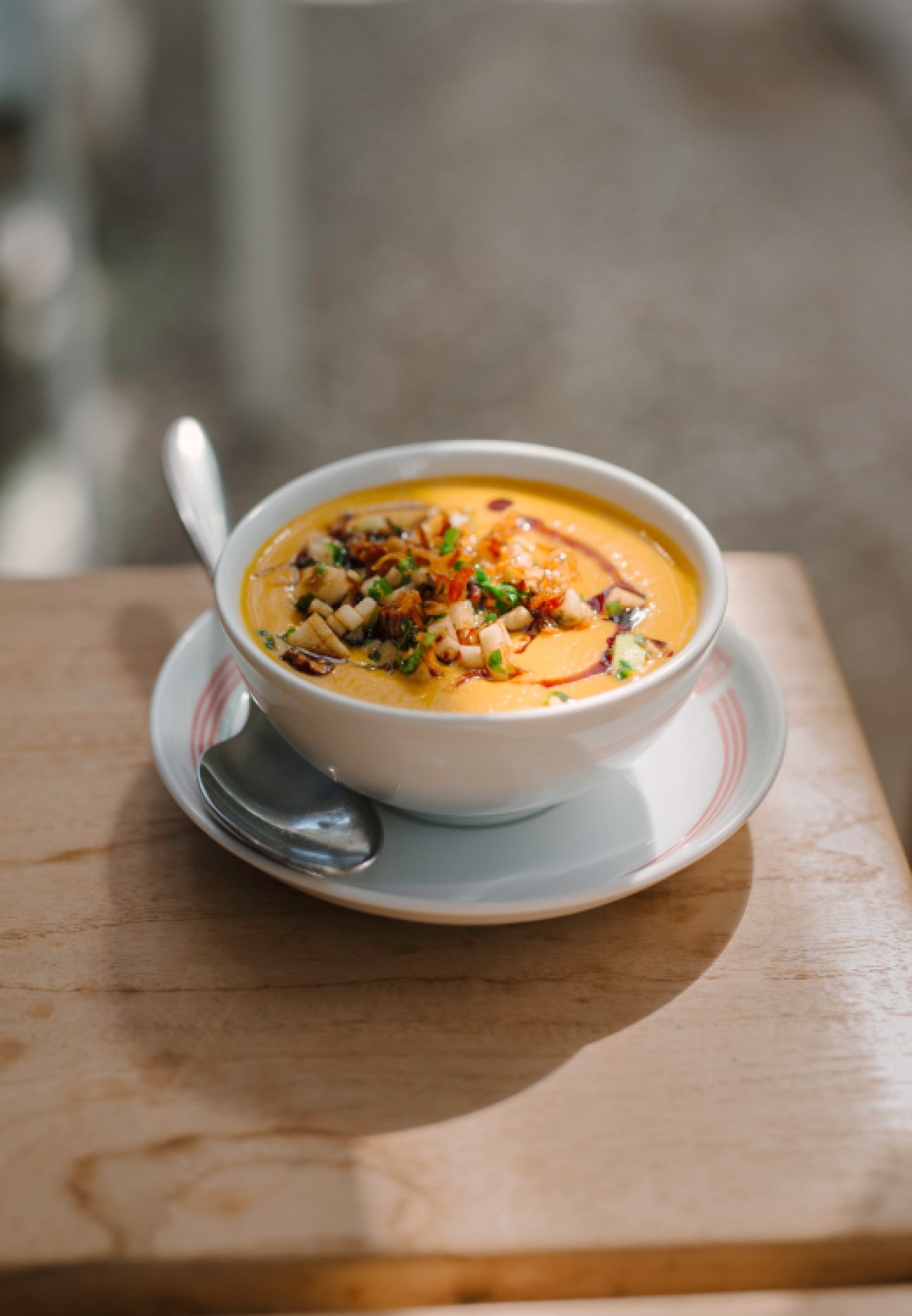 Bowl of yellow soup with mushrooms and herbs served in white bowl on wooden table