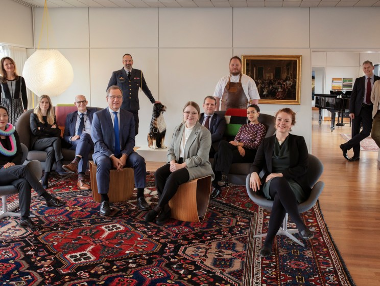 Group photo of Danish embassy staff in London seated and standing in modern office interior
