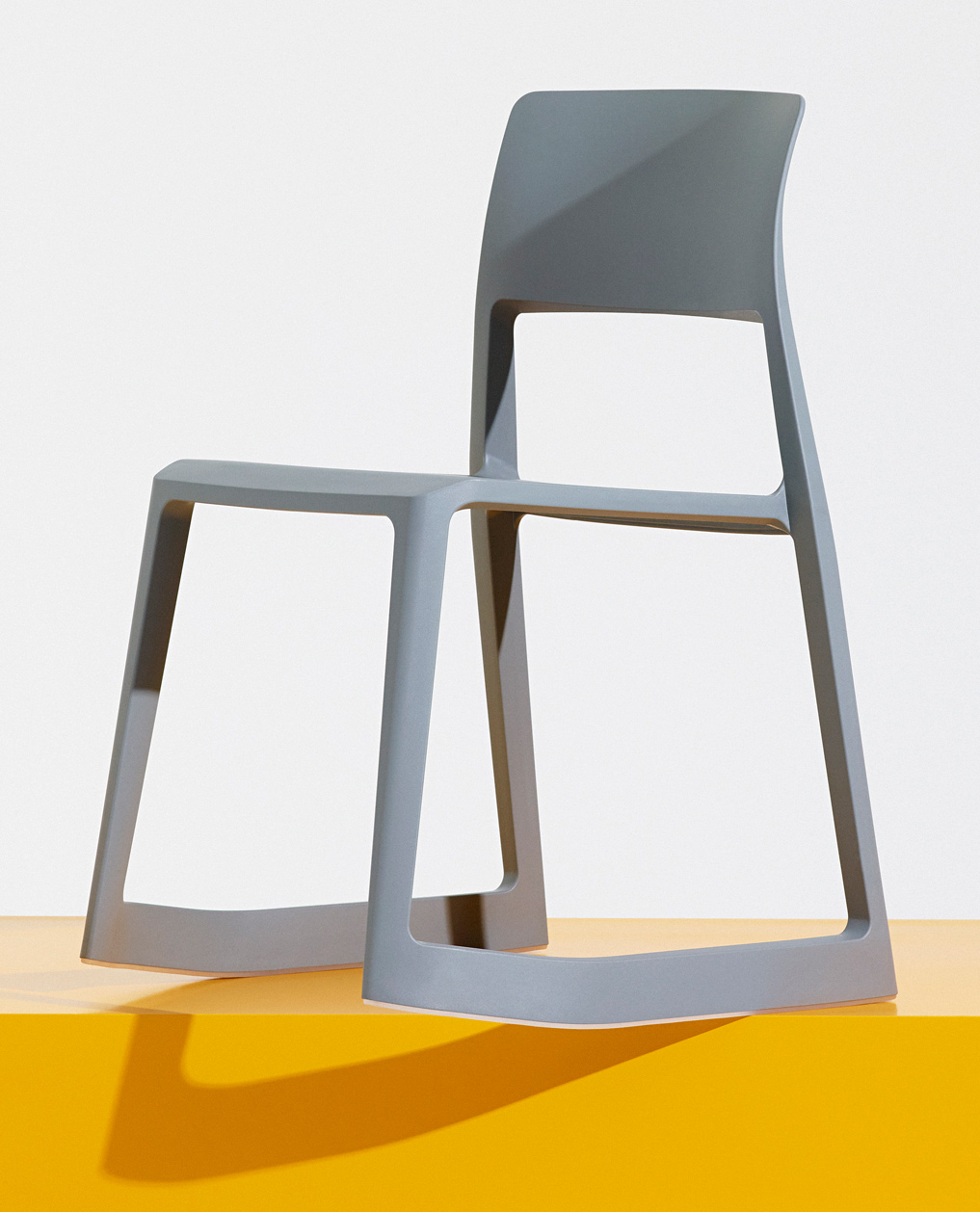 Gray molded plastic stacking chair with open frame design and curved backrest