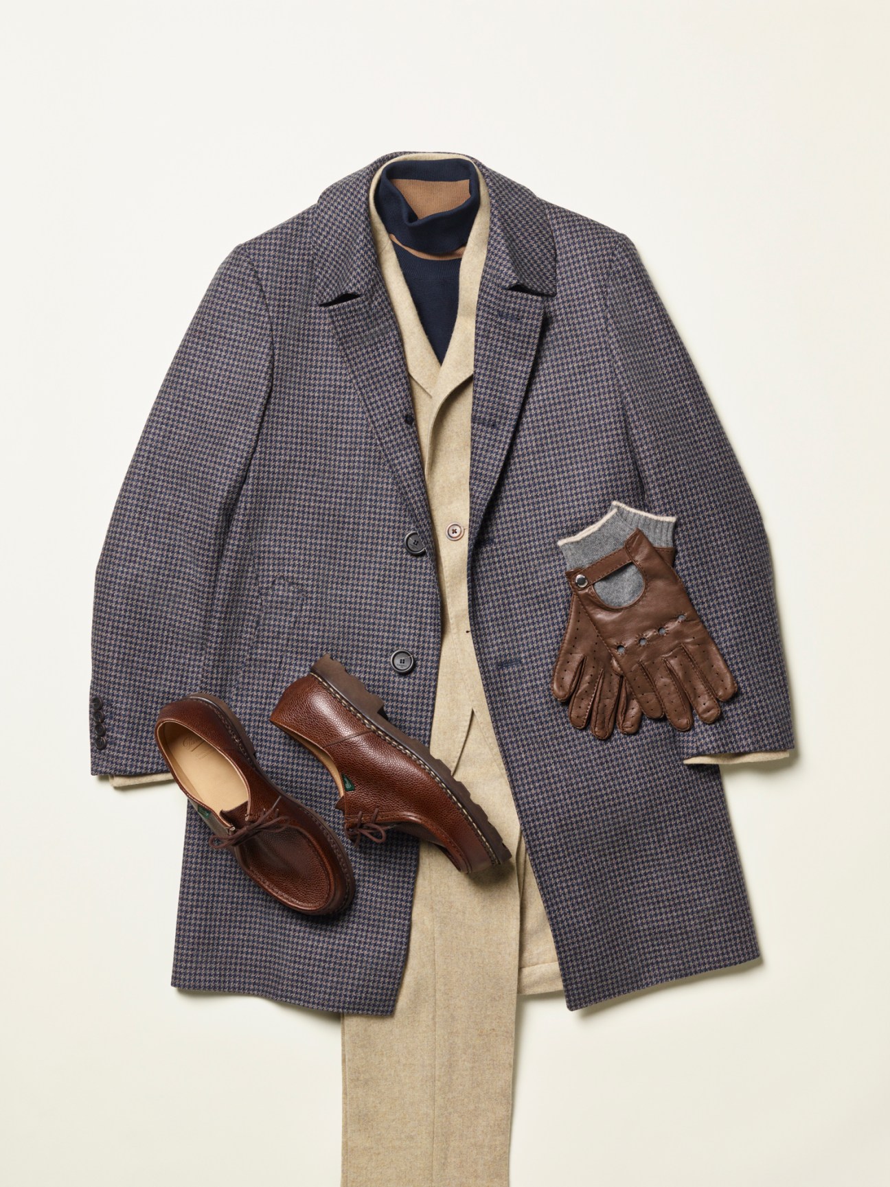Gray houndstooth coat arranged with cream cardigan, brown leather shoes and gloves on white background