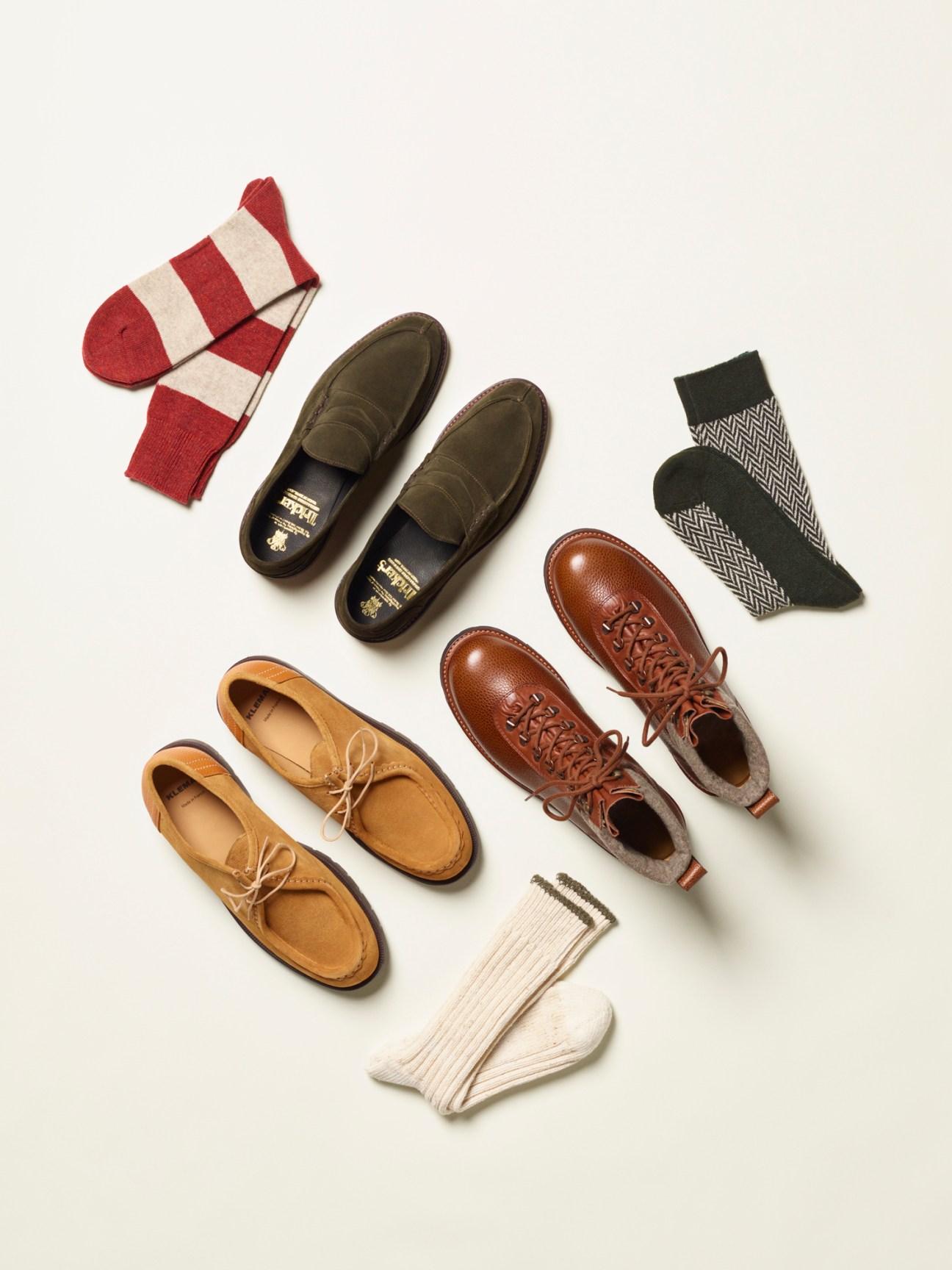 Three pairs of men's shoes in tan, olive, and brown leather displayed with striped and patterned socks