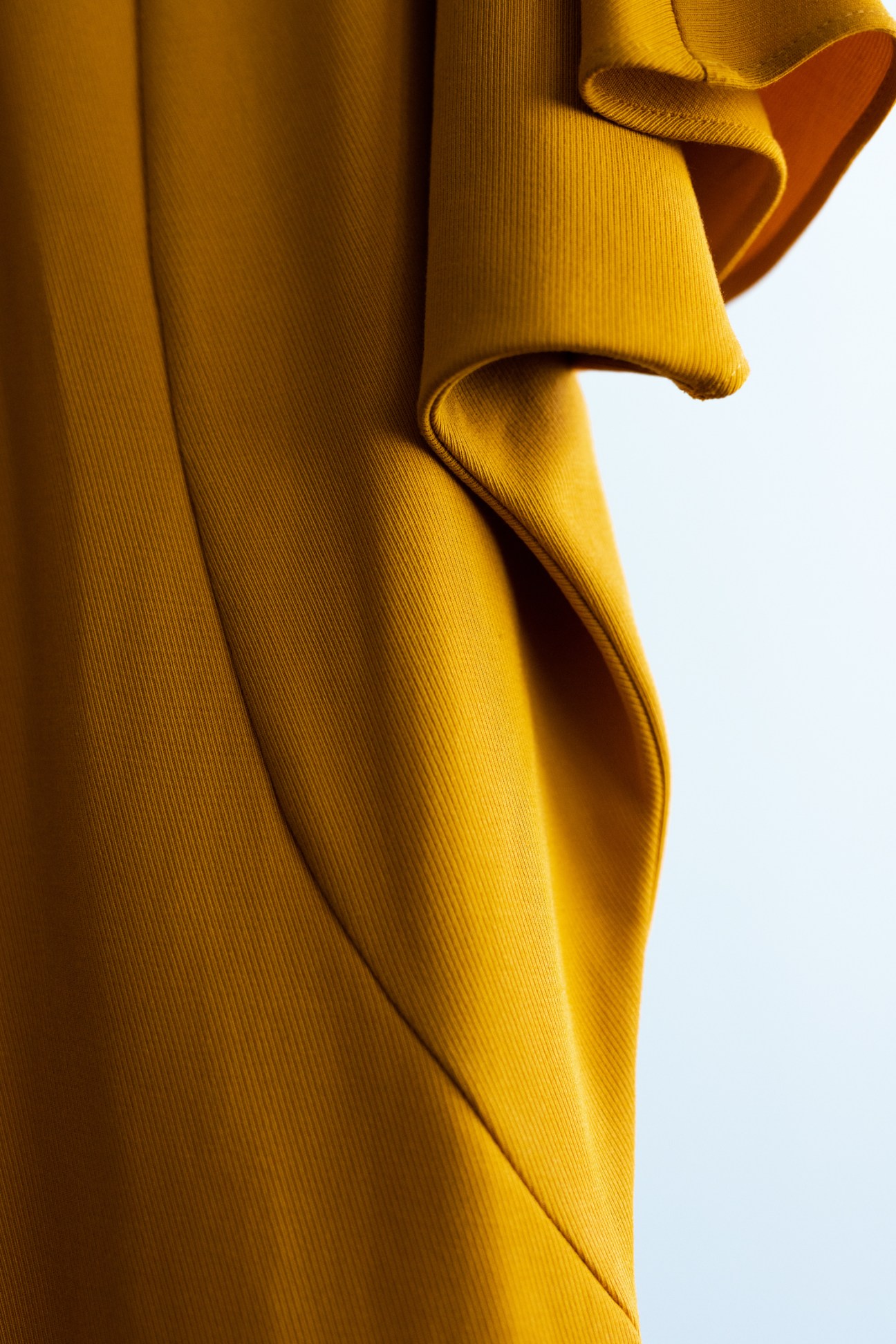 Golden ribbed fabric with flowing folds and curves against white background