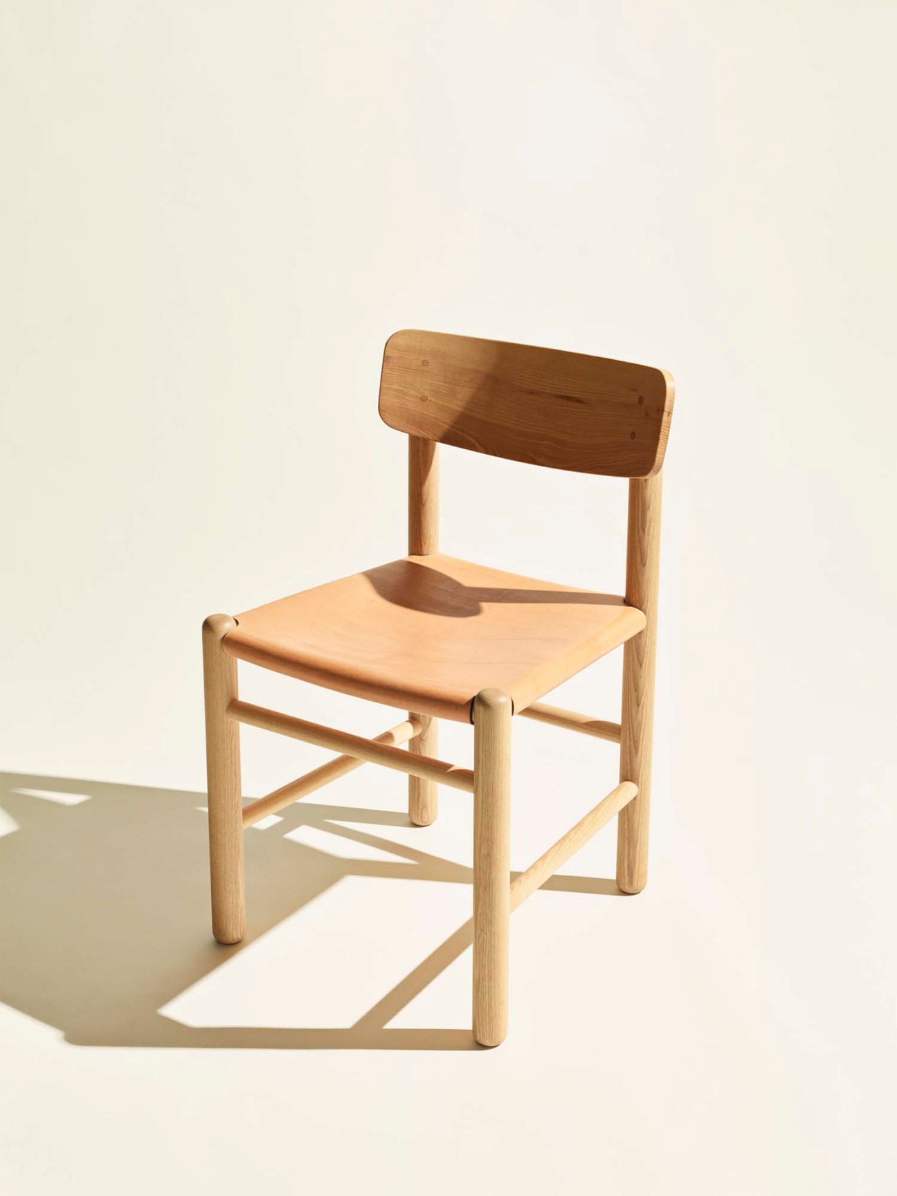 Syd dining chair by Another Country with natural wood frame and seat against cream background
