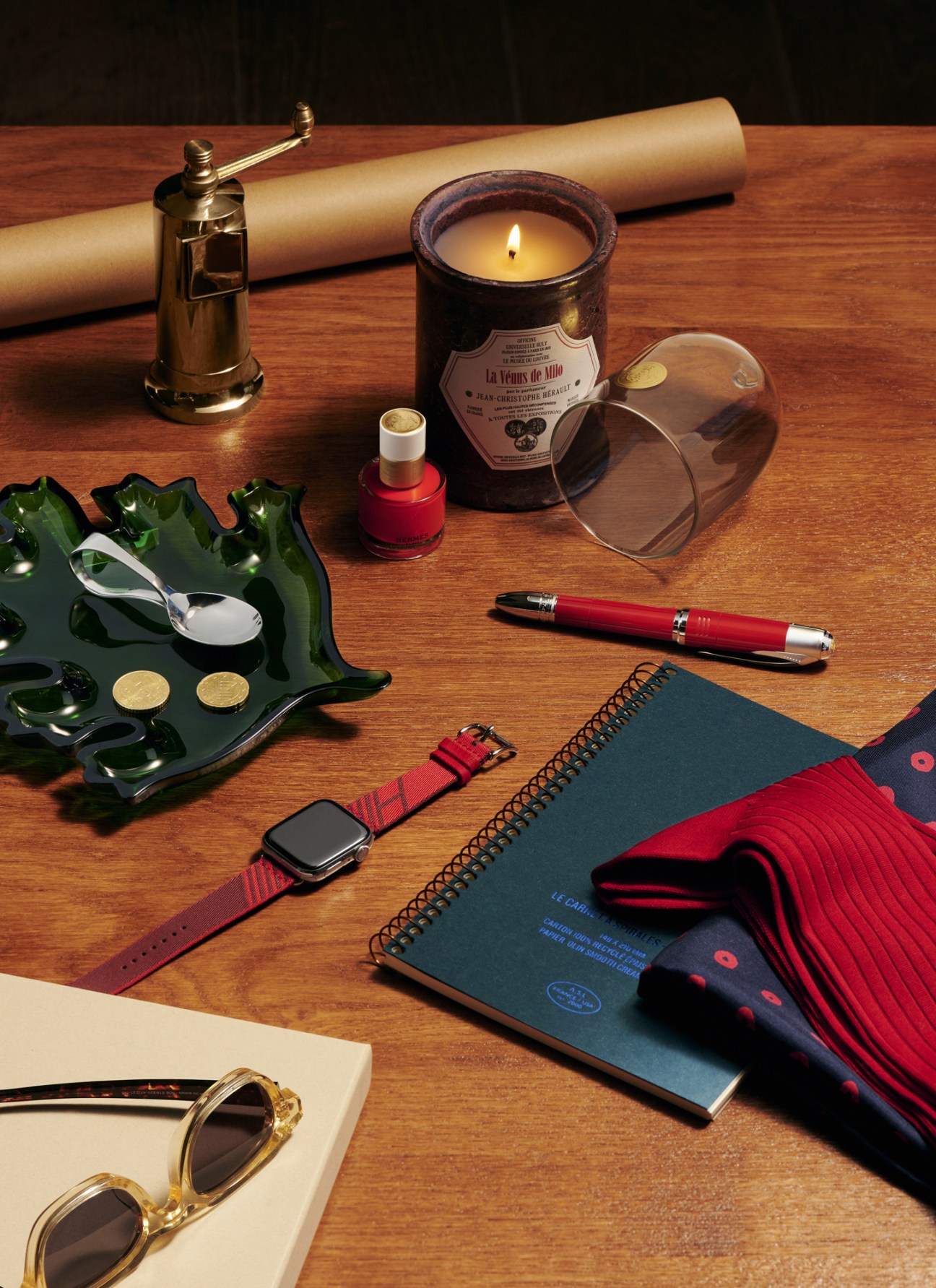 Luxury gift accessories arranged including pepper mill, nail polish, candle, spoon, watch, socks and other items
