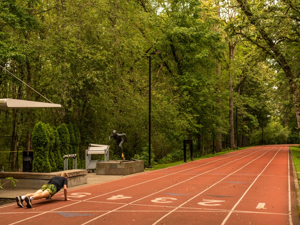 Person doing push-ups on outdoor running track with trees in background