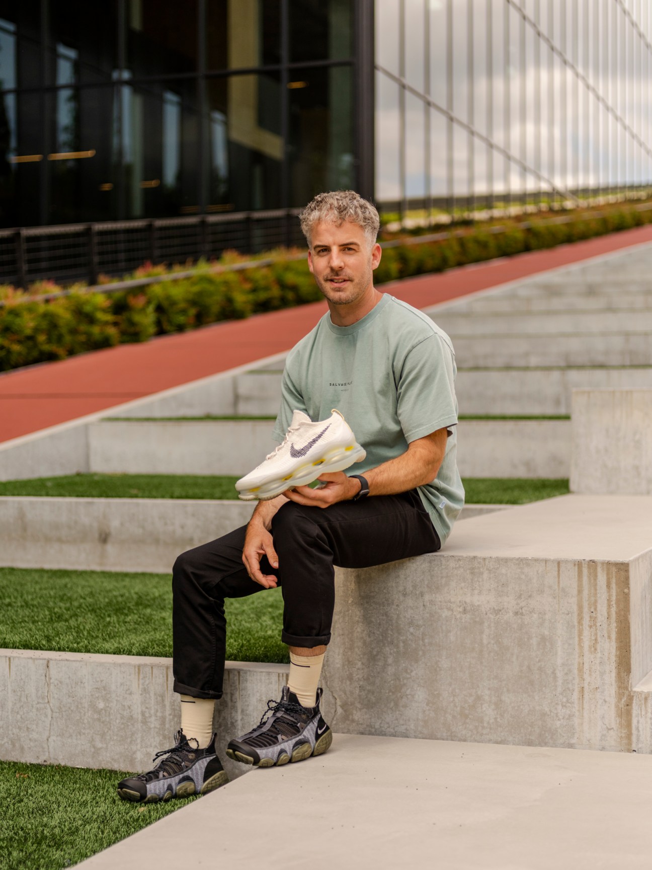 Phil Woodman, senior innovation designer for running at Nike, sitting outdoors holding a white Nike shoe