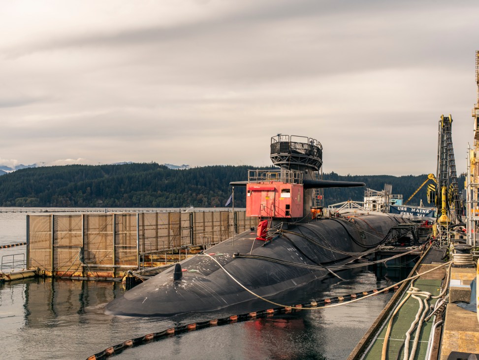 Nuclear submarine rising to the surface of dark water with crew members visible on the conning tower
