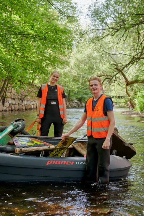 Volunteers in orange vests cleaning up the Akerselva river in Oslo