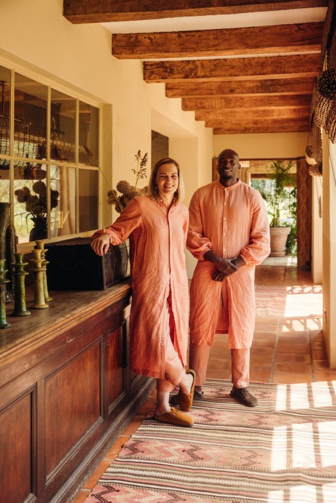 Staff members Alexa and Silent wearing matching orange robes standing in a hallway with exposed wooden beams