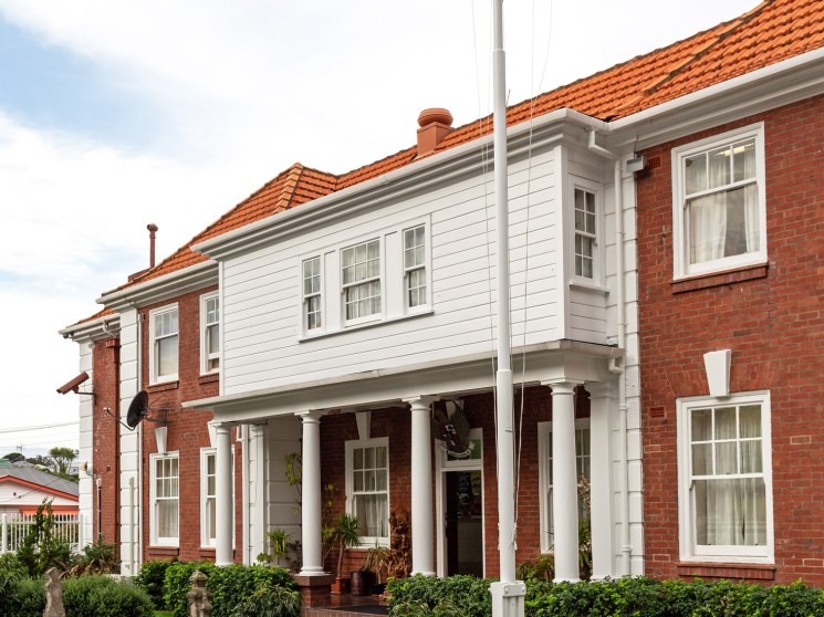 Red brick diplomatic building with white trim and Indonesian and Polish flags flying from a pole