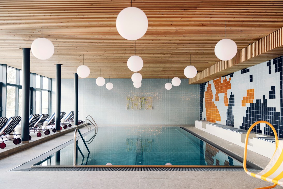 Indoor swimming pool with blue mosaic tiles, spherical pendant lights, and large windows overlooking mountain views