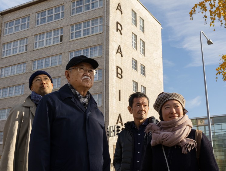 Four Japanese people in winter clothing standing outside the Arabia factory building in Helsinki