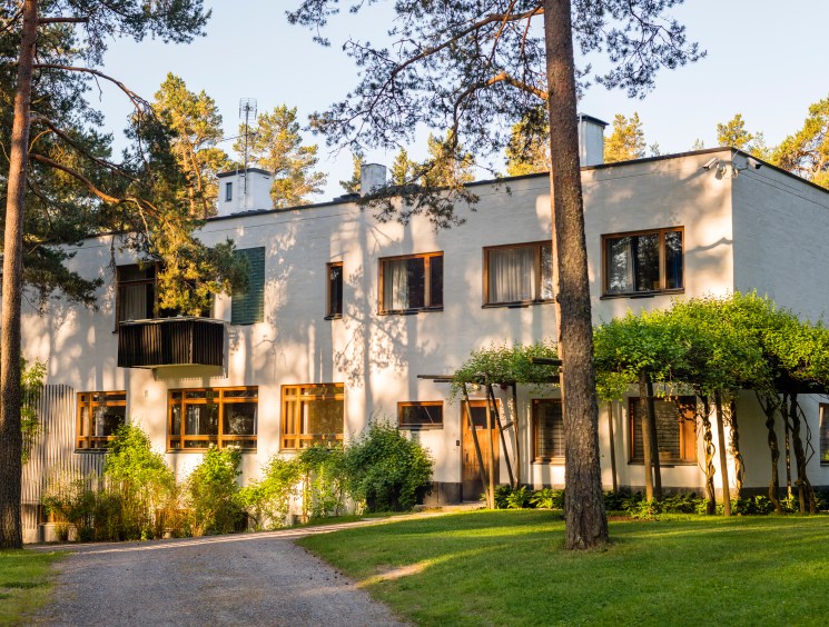 Villa Mairea exterior with white limestone and wood architecture surrounded by tall coniferous trees