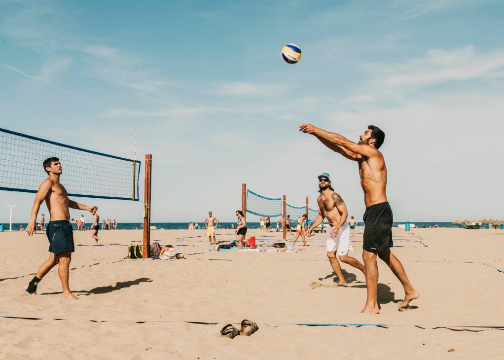 Beach volleyball players in action on sandy court with nets and spectators at Valencia beach