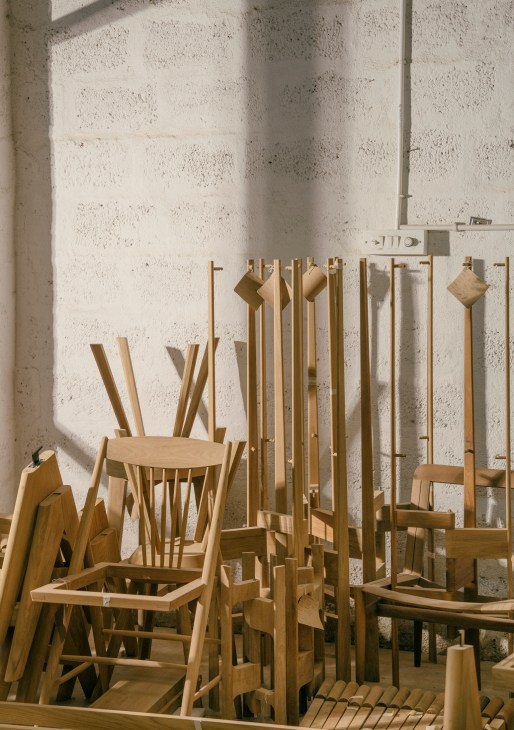 Workshop interior showing multiple wooden chairs in various stages of production
