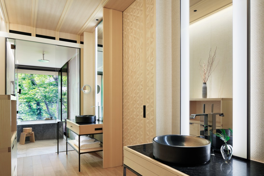 Modern bathroom at The Ritz-Carlton Nikko with black soaking tub, wooden vanity, and natural light from large window.