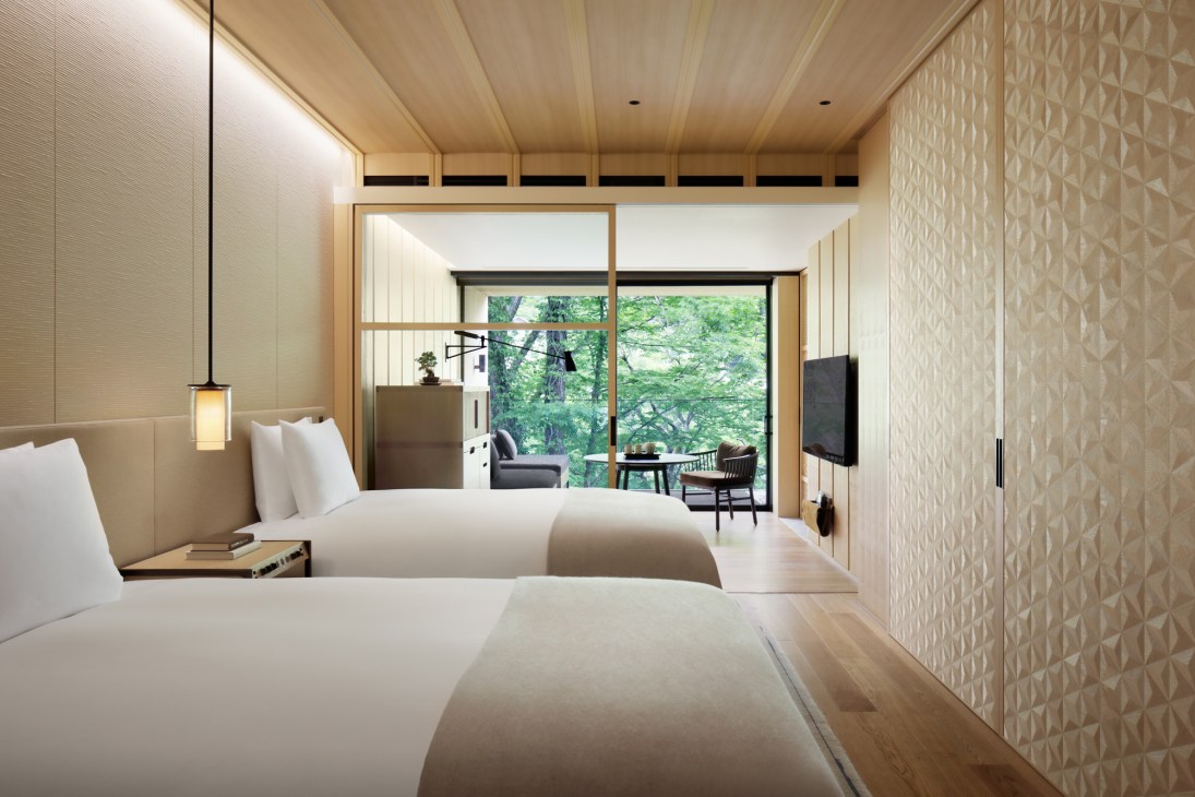 Modern Japanese hotel guest room with twin beds, wooden furnishings, and views of Mount Nantai through large windows at The Ritz-Carlton Nikko.
